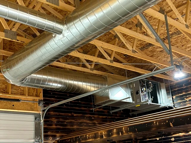 Metal ductwork and a commercial HVAC unit in an unfinished building