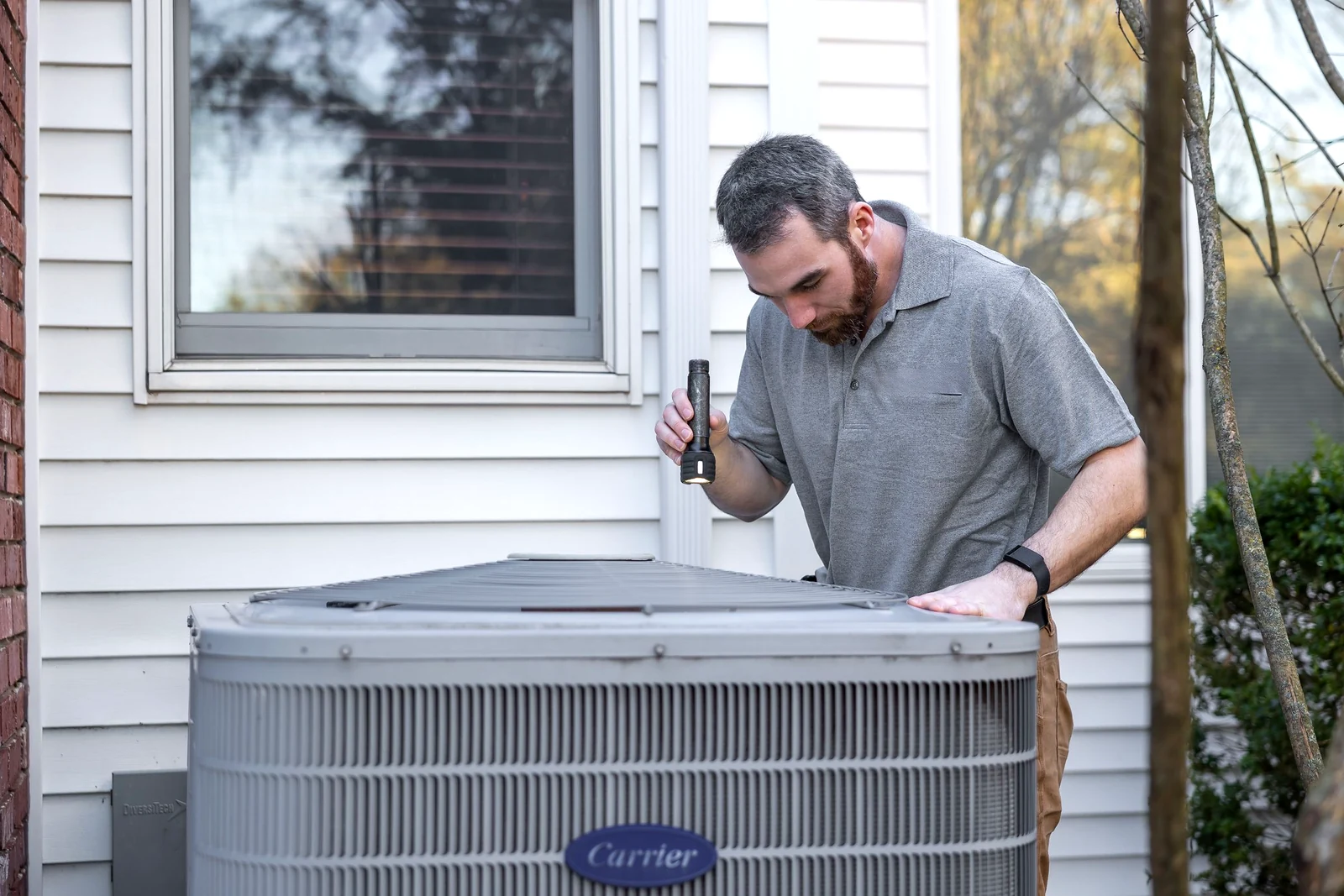 Technician inspecting an outdoor residential air conditioning unit